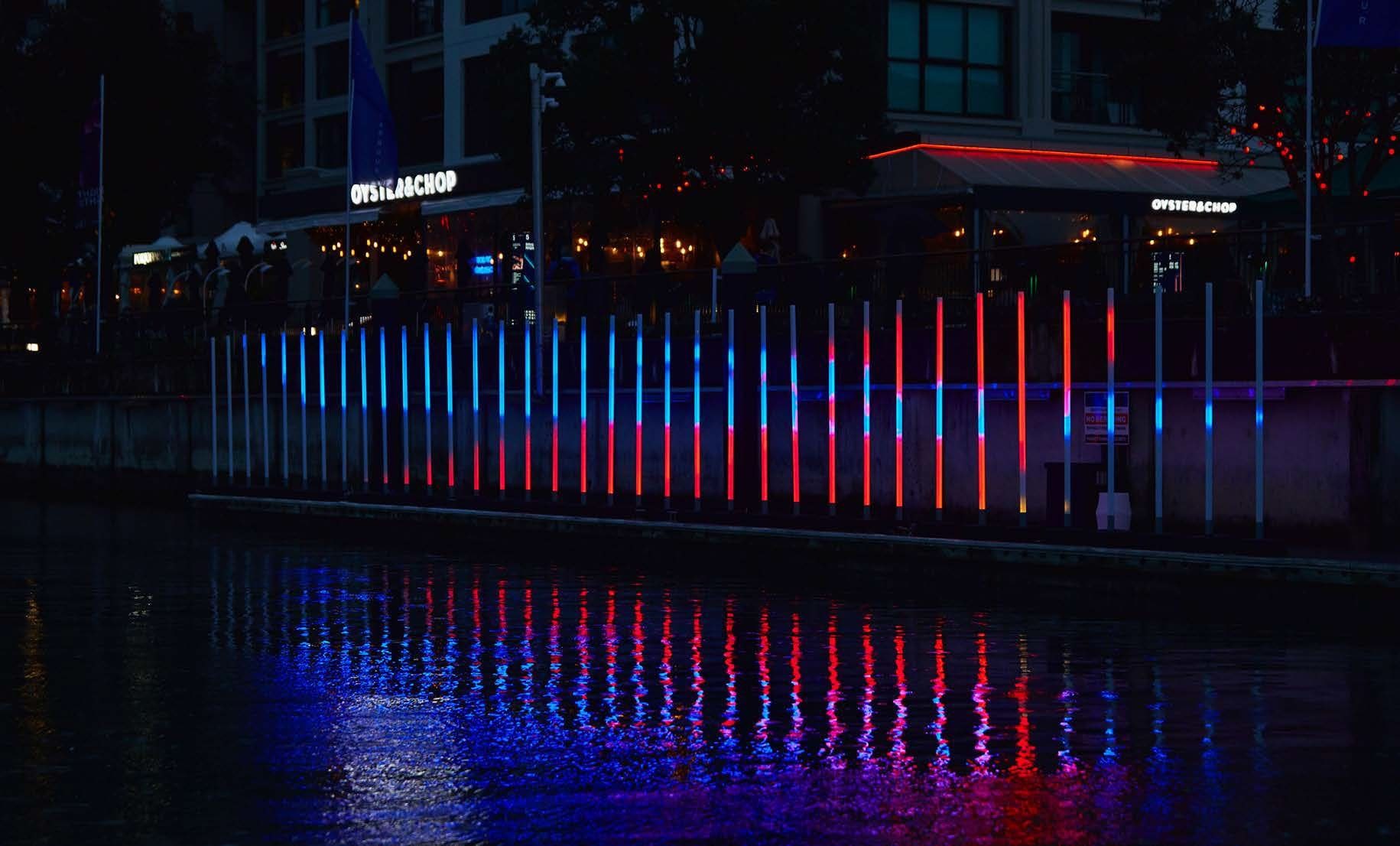 Viaduct Harbour light installation: columns of coloured light reflected in the water at night, Auckland